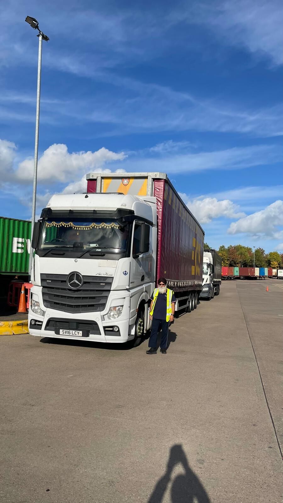 A URS Choices driver in high-visibility clothing at a container yard